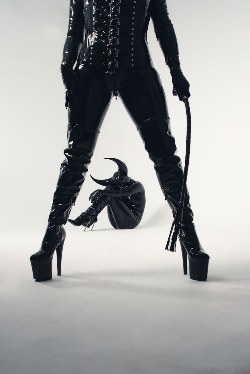 people in costume with devil horns and in leather pants standing with whip
